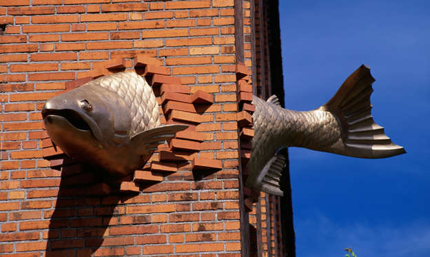Slide 2 de 19: A sculpture of a fish that seems to swim through a brick wall graces the corner of the South Park Seafood Grill on Salmon Street.
