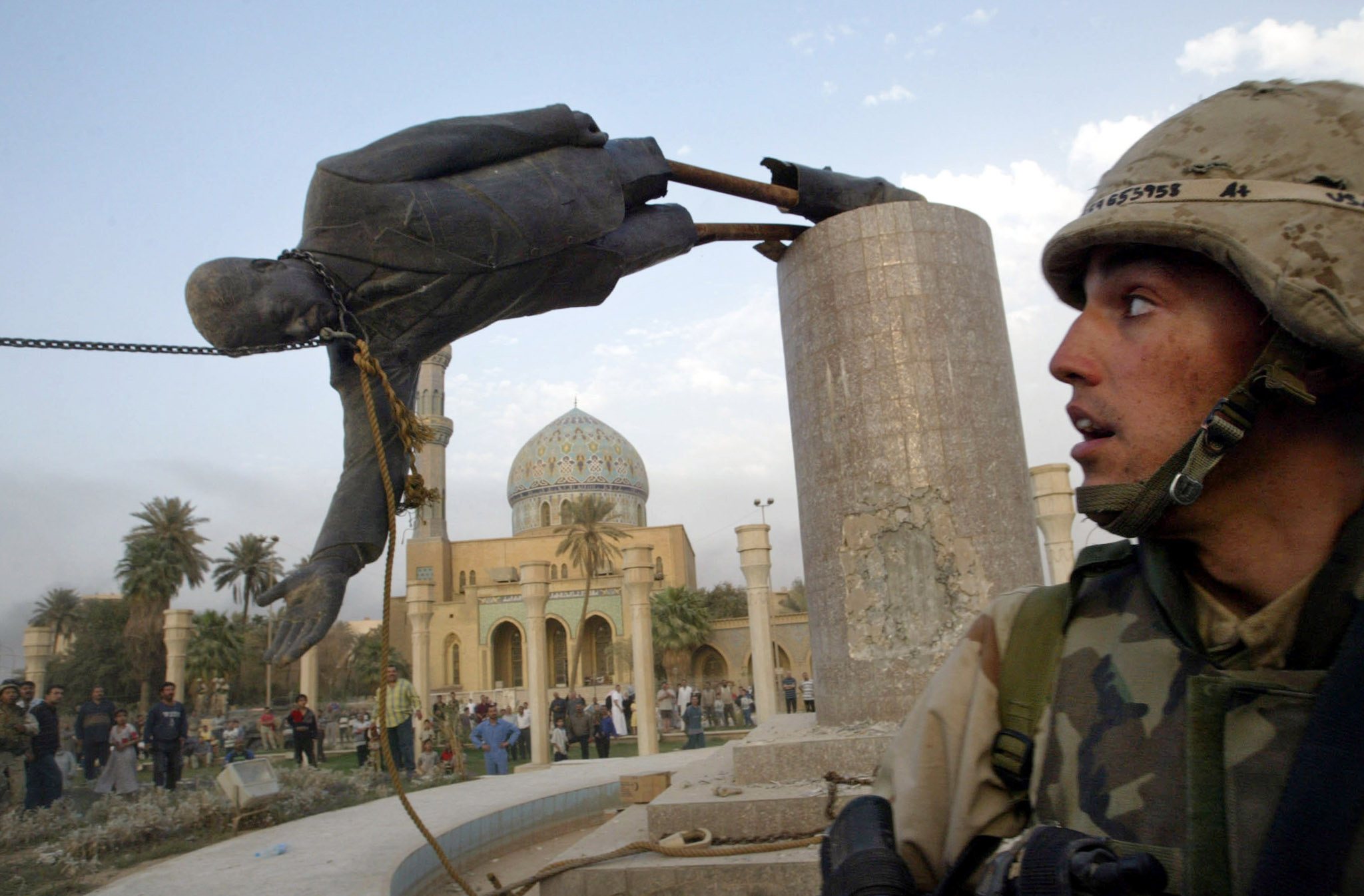 A U.S. soldier watches as a statue of Iraq's President Saddam Hussein falls in c...