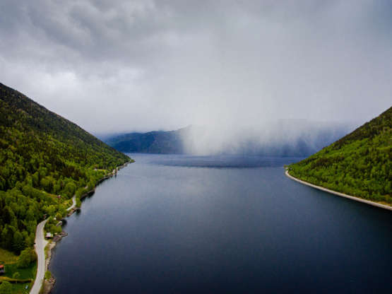 ÎÎ¹Î±ÏÎ¬Î½ÎµÎ¹Î± 42 Î±ÏÏ 100: Part of the Lake Tinn in Rjukan, surrounded by mountains. The water is calm and the fog is falling over the lake. The photo was taken from a high angle view using a drone. Lake Tinn is one of the largest lakes in Norway. It is situated between the munic