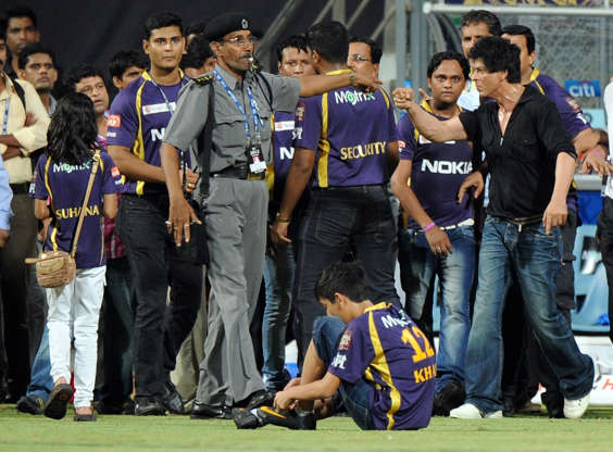 Slide 9 of 20: Bollywood actor and Indian Premier League franchise Kolkata Knight Riders co-owner Shah Rukh Khan (R) gestures as a security guard blows a whistle and directs kids accompanying him off the playing field after the IPL Twenty20 cricket match between Mumbai